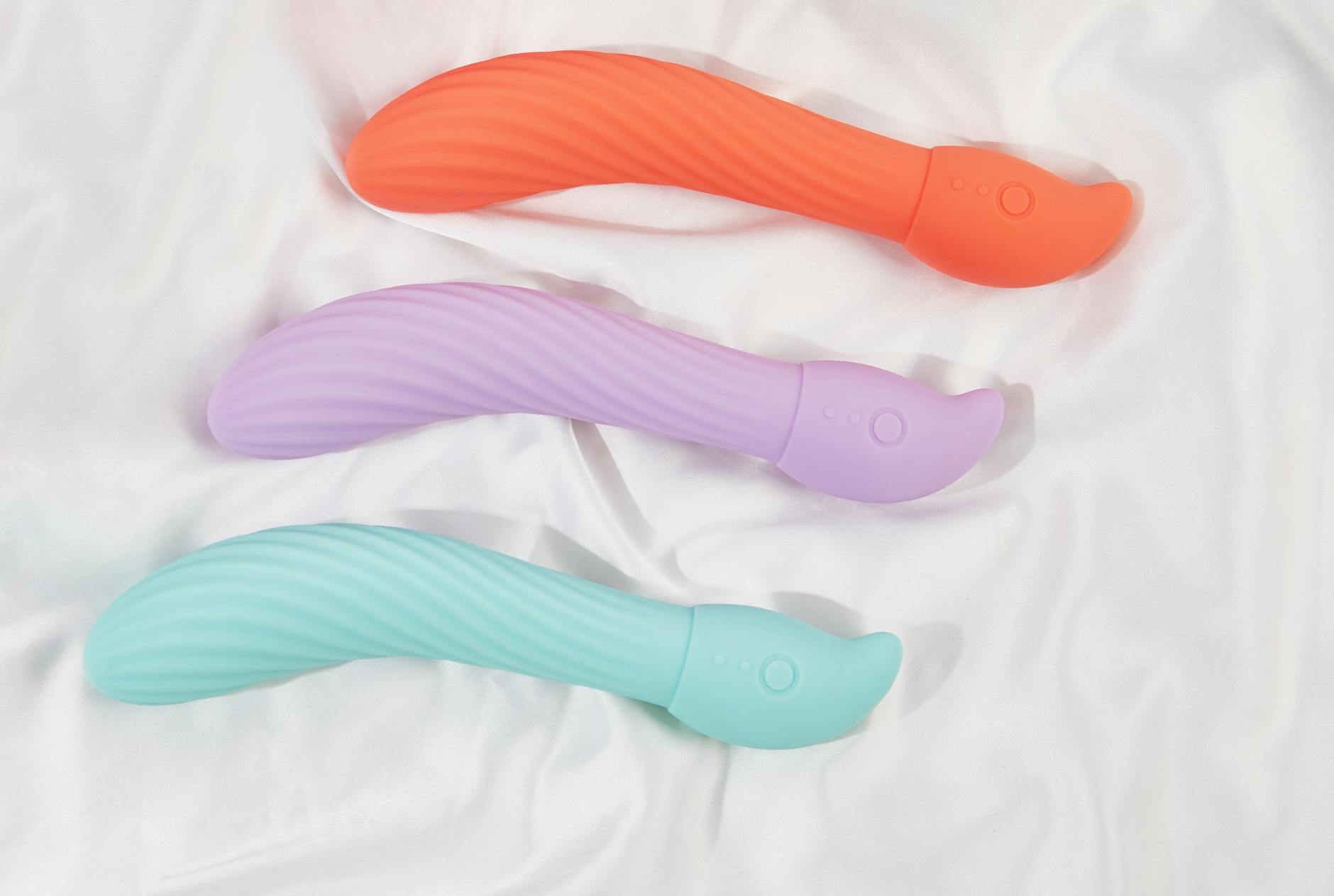 A teal clitoral vibrator on smooth white silk fabric, representing beginner-friendly toys