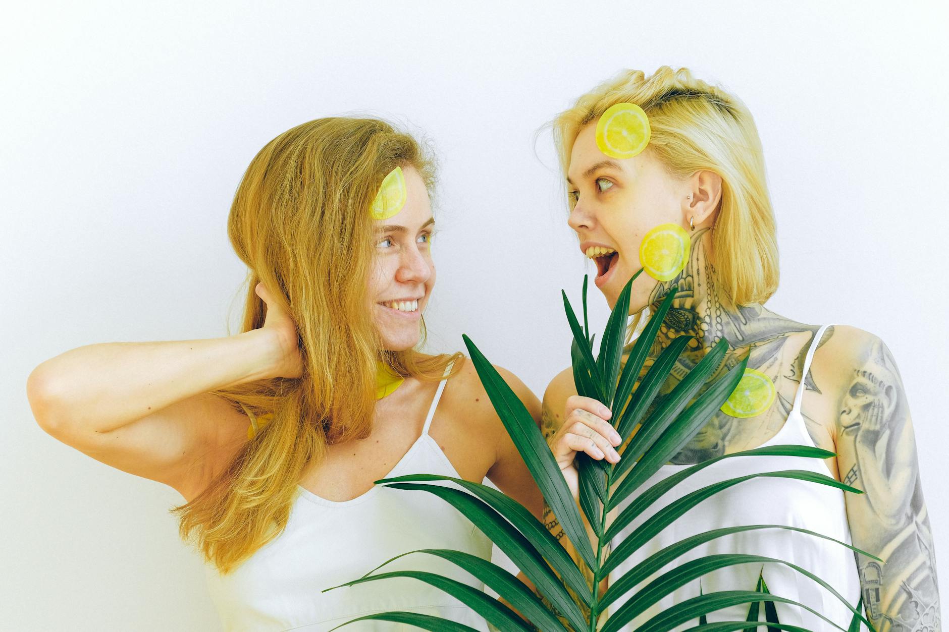 Two women smiling together with fresh lemons, expressing joy and comfort in their relationship.