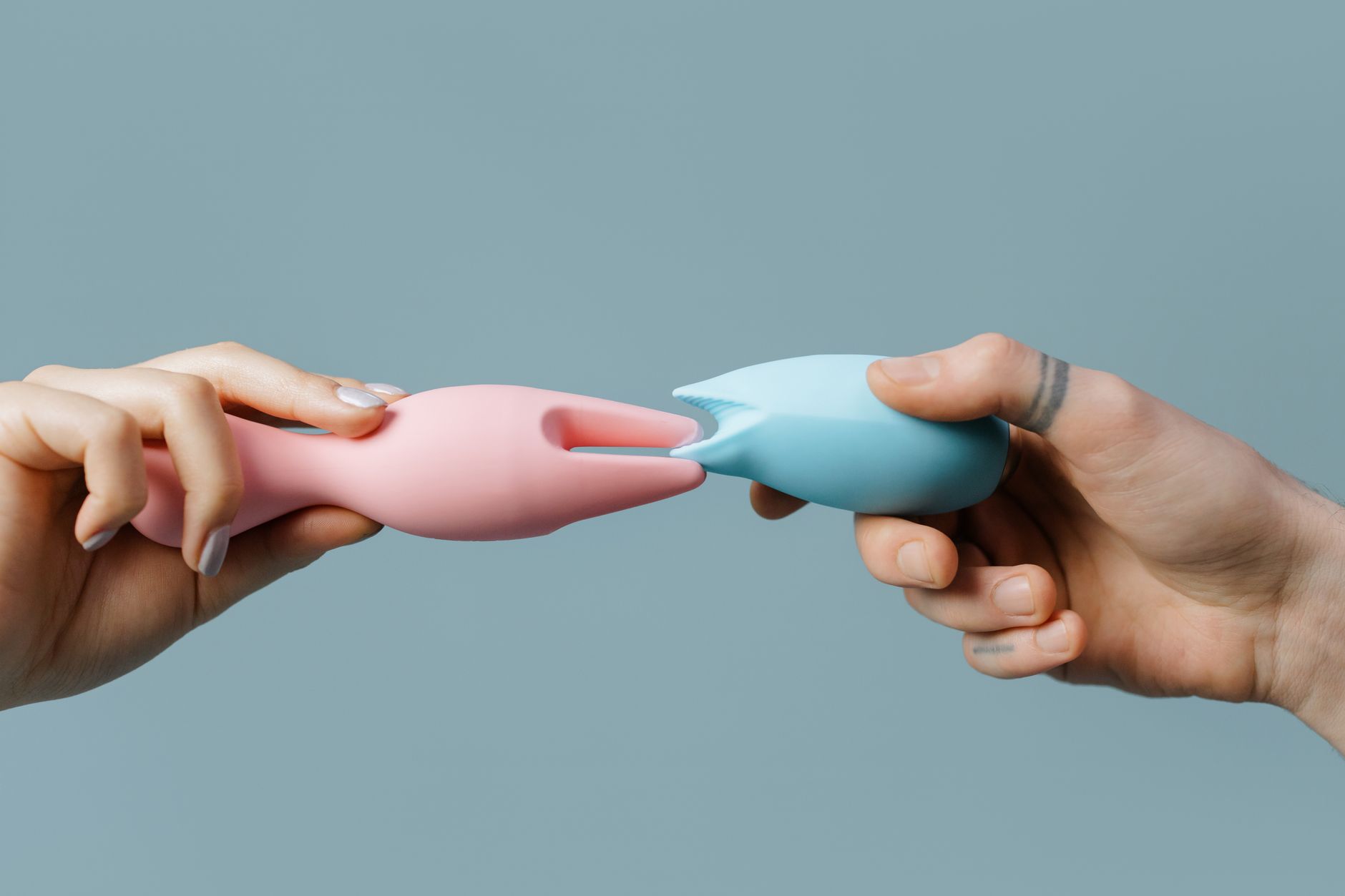Hands holding silicone vibrators in a calm, assured way against a soft background