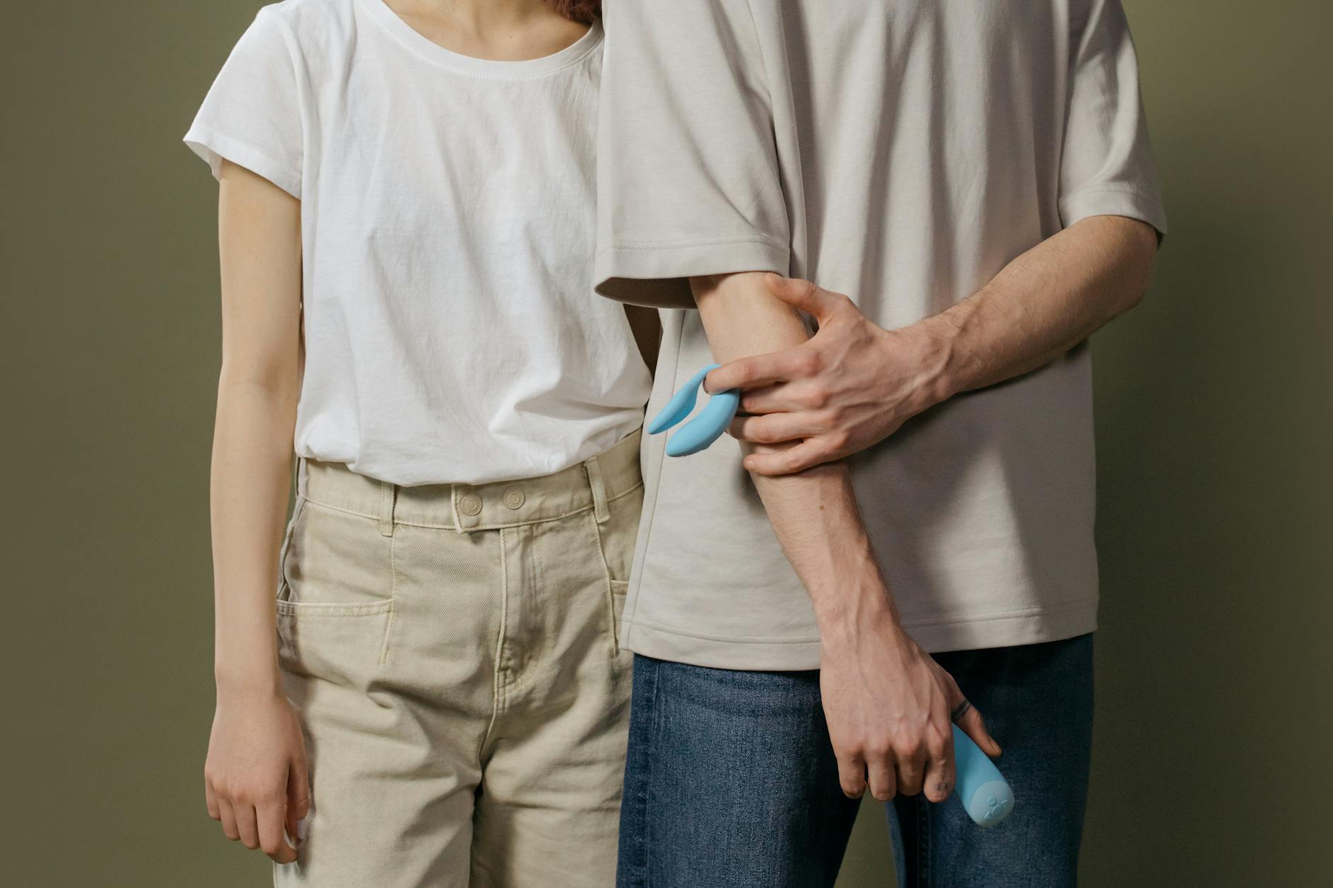 A couple standing together indoors, learning to use a clitoral vibrator as part of their intimate practice