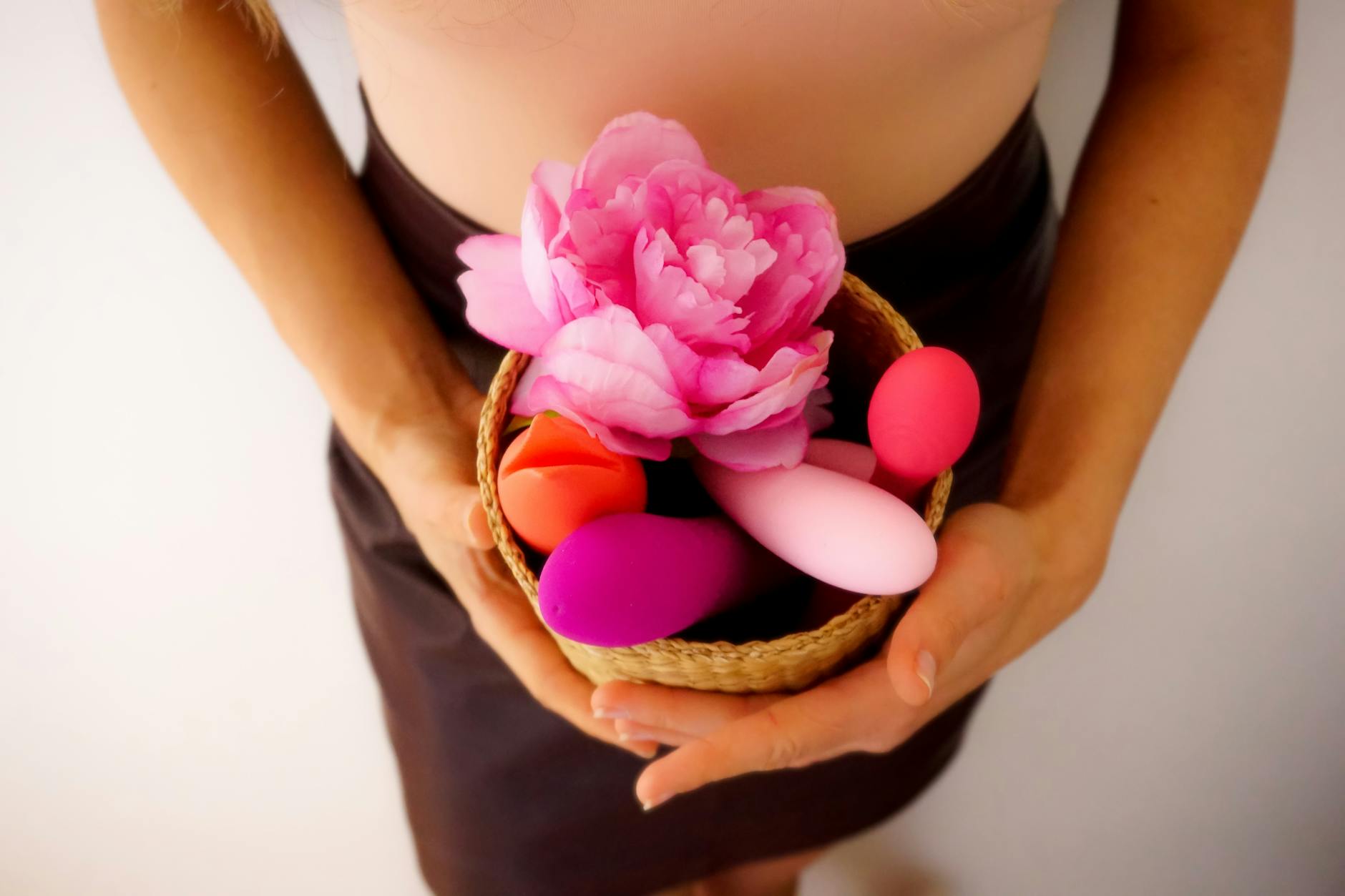 Colorful vibrators in a basket with fresh flowers, symbolizing the return of pleasure